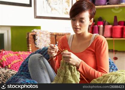 Young Woman Sitting In Chair Knitting
