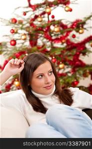 Young woman sitting in front of Christmas tree on sofa