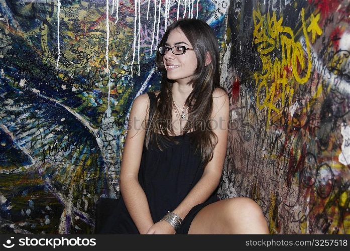 Young woman sitting in front of graffiti wall