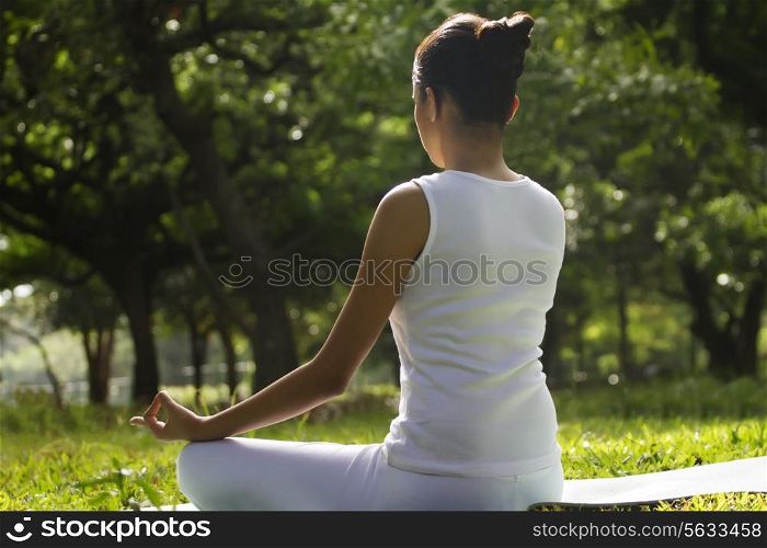 Young woman sitting in lotus position in a park