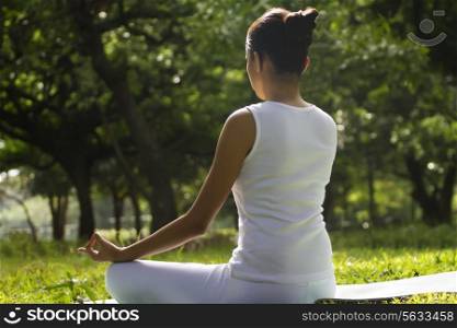 Young woman sitting in lotus position in a park