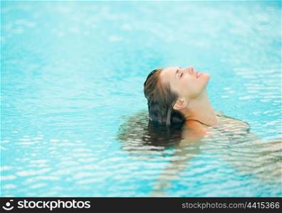 Young woman sitting in pool and relaxing