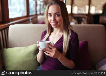 Young woman sitting in the cafe with a cup of beverage.