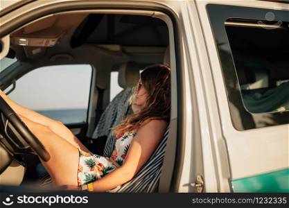 Young woman sitting in the driver&rsquo;s seat in a van with mini dress