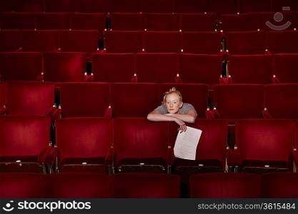 Young woman sitting in theatre stalls