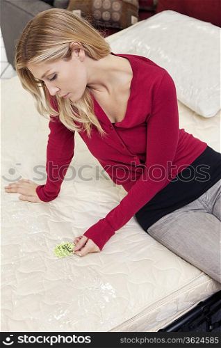 Young woman sitting mattress while looking at price tag