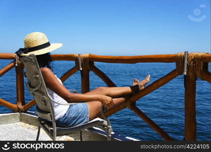 Young woman sitting on a balcony looking over the ocean enjoying the view