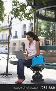 Young woman sitting on a bench and using a laptop, Old San Juan, San Juan, Puerto Rico