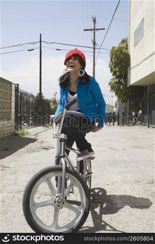 Young woman sitting on a bicycle and laughing