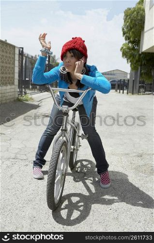 Young woman sitting on a bicycle and talking on a mobile phone