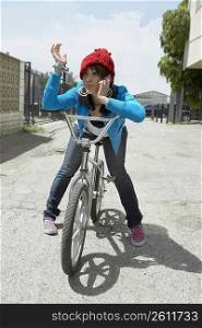 Young woman sitting on a bicycle and talking on a mobile phone