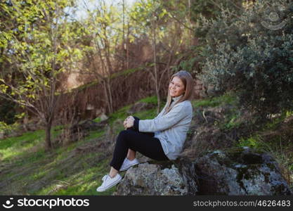 Young woman sitting on a big stone in a relaxed day