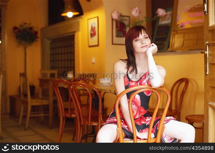 Young woman sitting on a chair with her hand on her chin