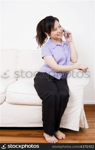 Young woman sitting on a couch and talking on a mobile phone