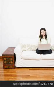 Young woman sitting on a couch and using a laptop