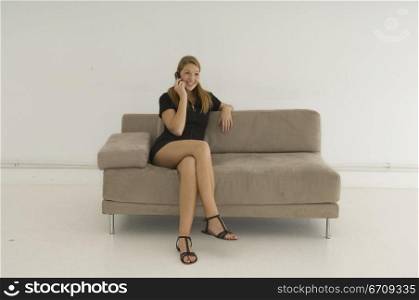 Young woman sitting on a couch and using a mobile phone