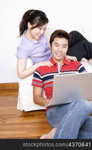 Young woman sitting on a couch with a mid adult man using a laptop