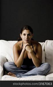 Young woman sitting on a couch with her hands on her chin