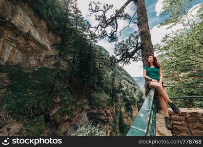 Young woman sitting on a fence observes the forest