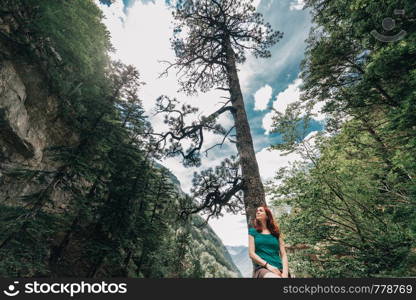 Young woman sitting on a fence observes the forest