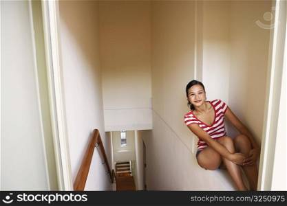 Young woman sitting on a ledge and smiling