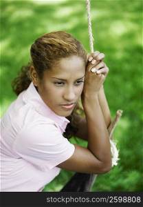 Young woman sitting on a rope swing