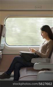 Young woman sitting on a train using her phone