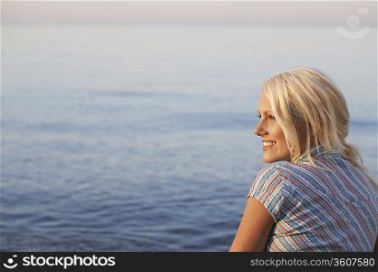 Young woman sitting on beach, side view