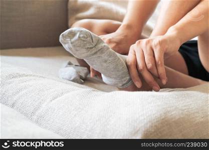 Young woman sitting on bed wearing soft gray socks