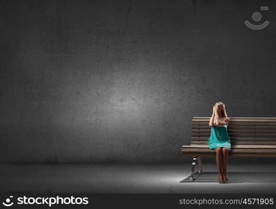 Young woman sitting on bench closing eyes with palms. Alone with fears