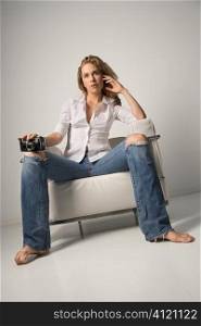 Young Woman Sitting on Chair and Holding Camera