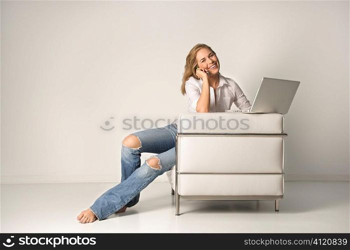 Young Woman Sitting on Chair with a Laptop and Cell Phone