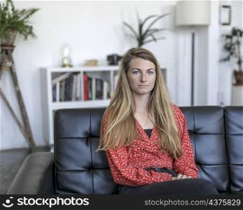 Young woman sitting on couch a home.