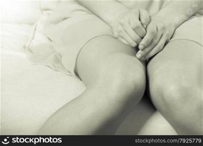 Young woman sitting on couch, only the legs and the lap is showing, she is shy, closeup