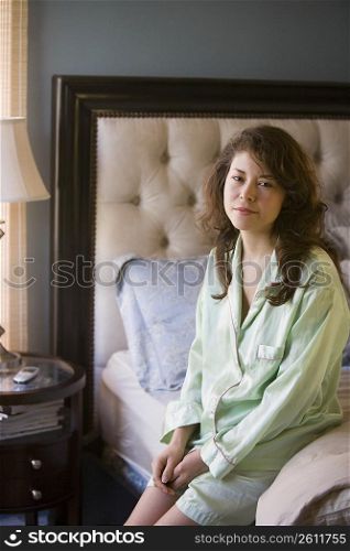 Young woman sitting on edge of bed
