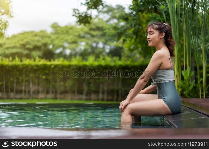 young woman sitting on edge of swimming pool