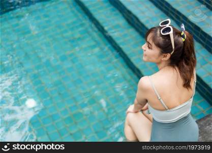 young woman sitting on edge of swimming pool