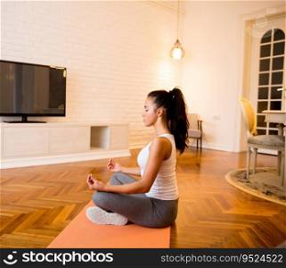 Young woman sitting on floor at home doing yoga meditation