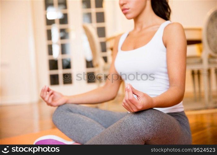 Young woman sitting on floor at home doing yoga meditation