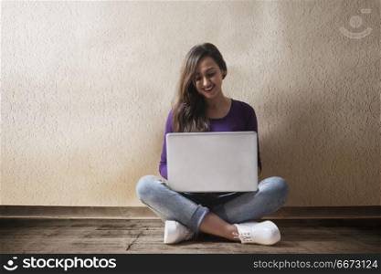 Young woman sitting on floor using laptop