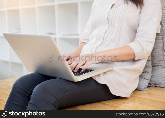 Young woman sitting on floor with laptop in library, education and technology concept