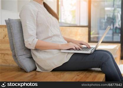 Young woman sitting on floor with laptop in library, education and technology concept