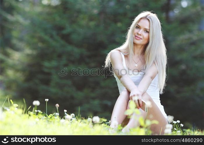 young woman sitting on grass. young blond woman sitting on grass