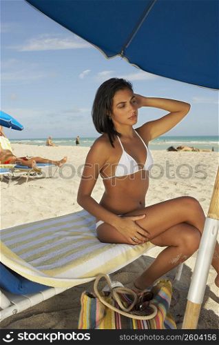 Young woman sitting on lawn chair on beach