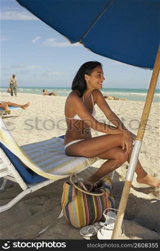 Young woman sitting on lawn chair on beach
