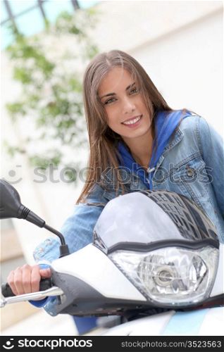 Young woman sitting on motorbike outside