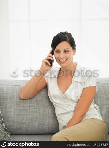 Young woman sitting on sofa and talking mobile phone