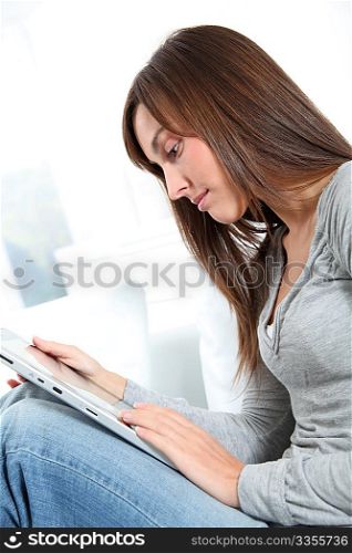 Young woman sitting on sofa with electronic pad