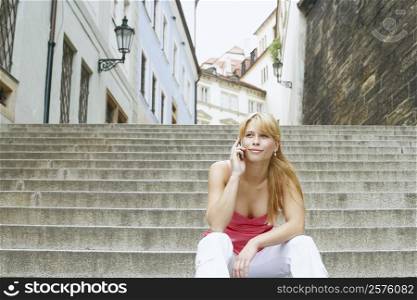 Young woman sitting on steps and talking on a mobile phone