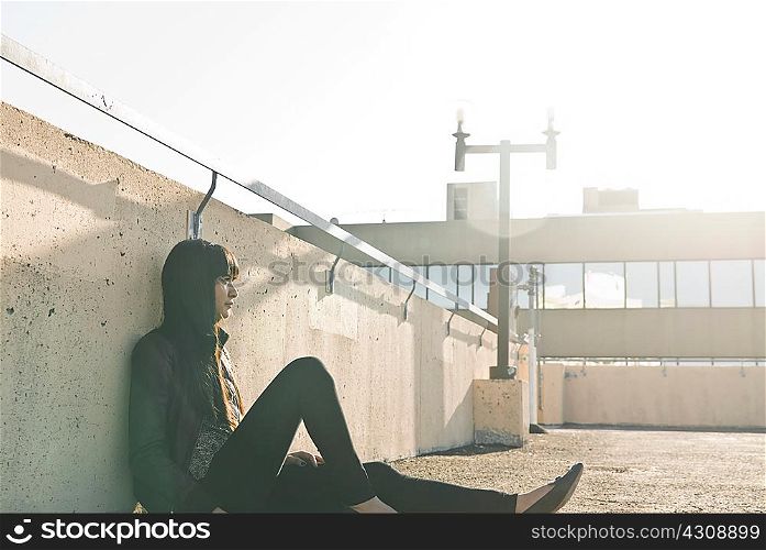 Young woman sitting on sunlit rooftop